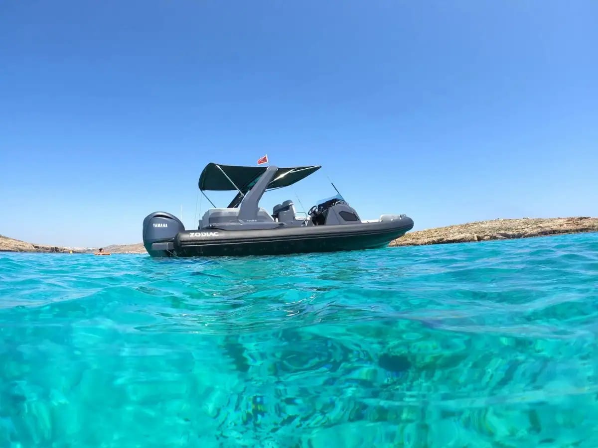 A grey RIB resting on bright blue water
