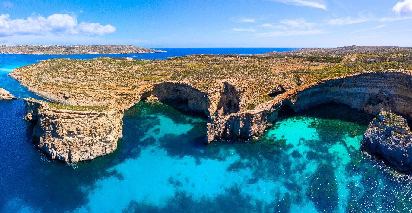 A rock arch over deep blue water on Comino