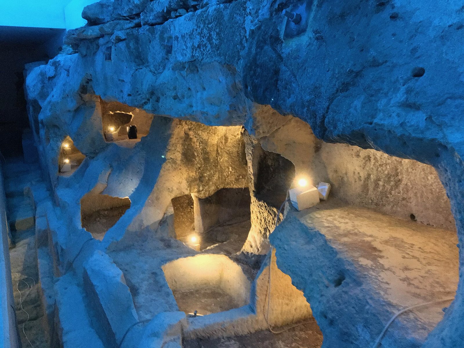 Rock-cut tombs at Ta' Bistra Catacombs in Mosta, lit from within beneath the protective shelter