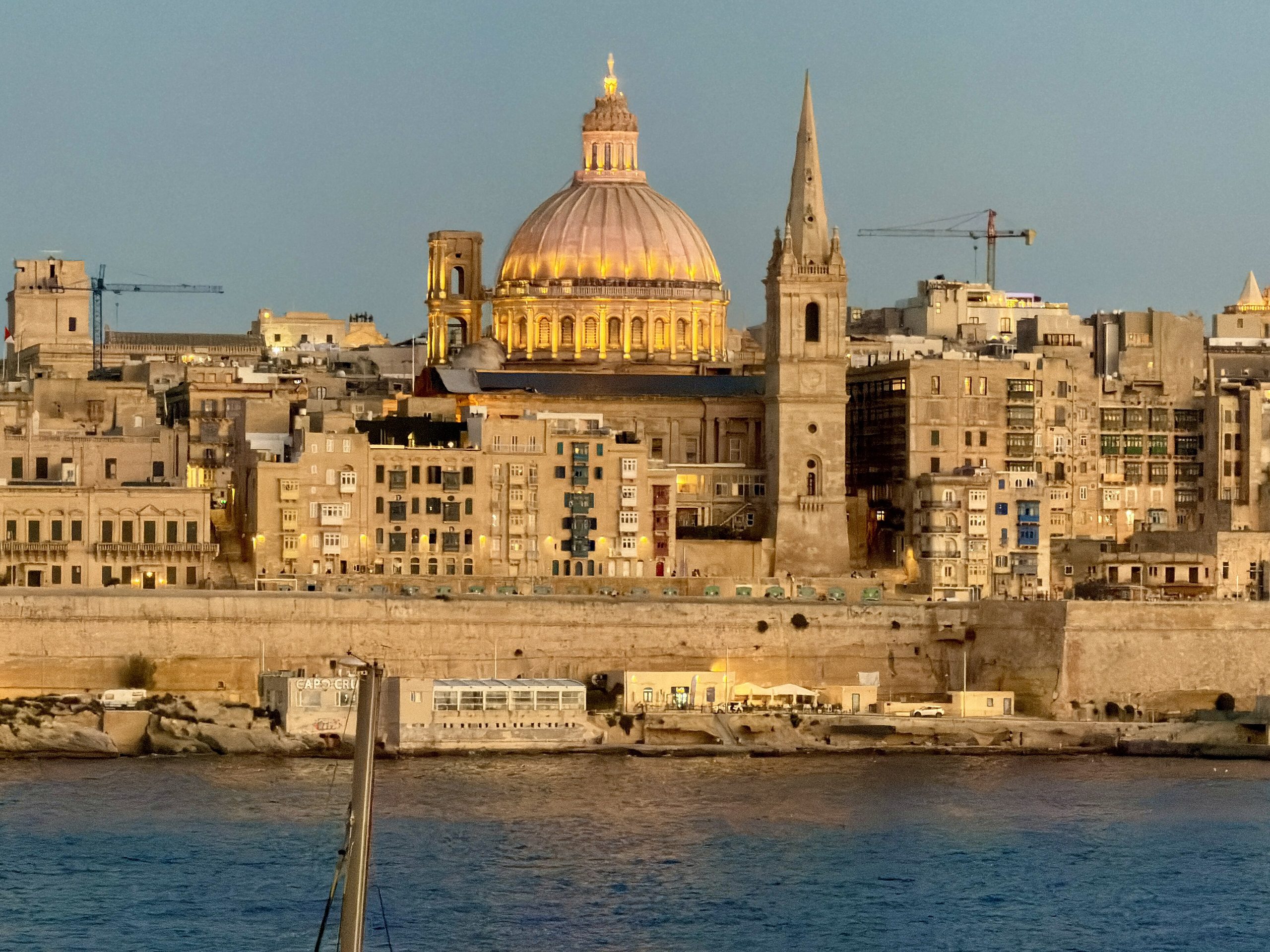 Valletta skyline at blue hour from Sliema, with the floodlit dome of the Carmelite Basilica above the bastions