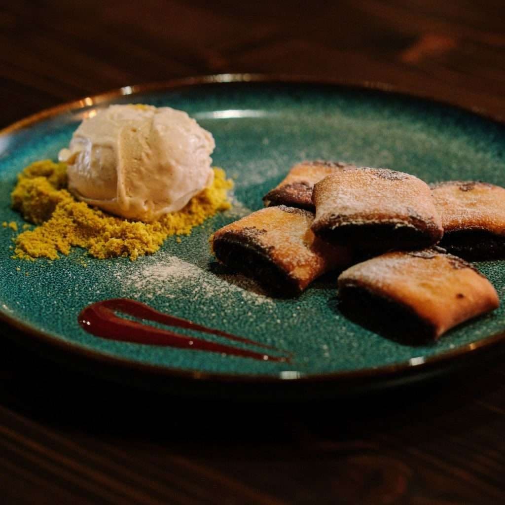 A dessert of pastry parcels with ice cream on a teal plate