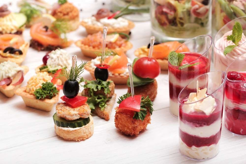 A platter of canapes and small desserts in glasses