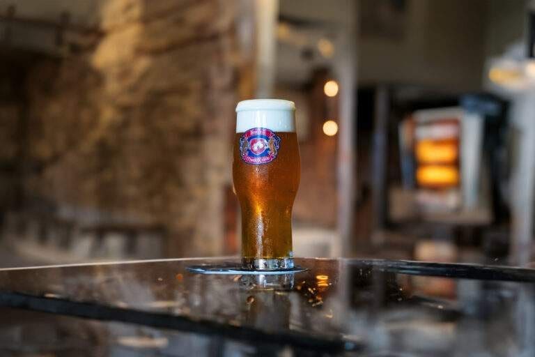 A glass of beer on a polished counter with a blurred stone interior behind