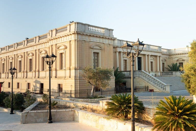 The sandstone front of a grand Montekristo building with balustrades, lamp posts and a wide stone staircase