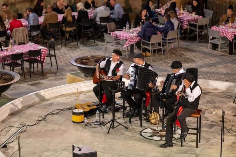Musicians playing accordions and guitars at a courtyard dinner