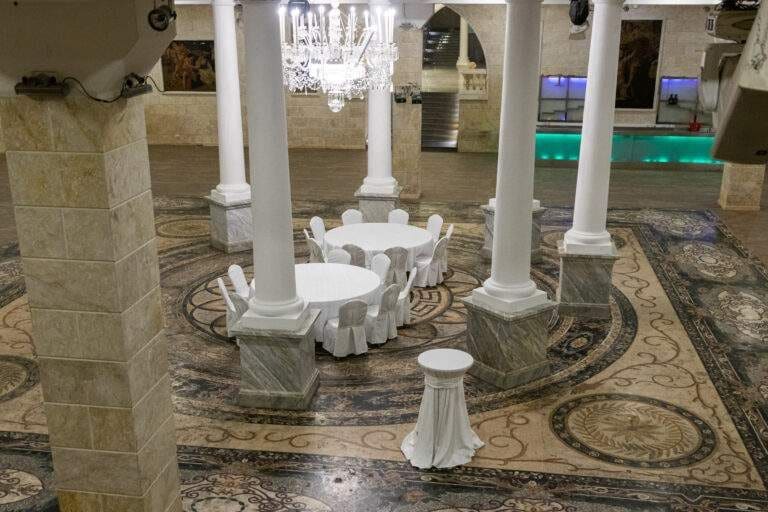 Round tables among white columns on a mosaic floor in The Renaissance