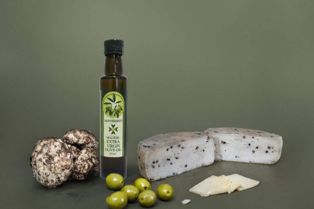 Montekristo extra virgin olive oil beside a peppered cheese, a cheese wedge and green olives