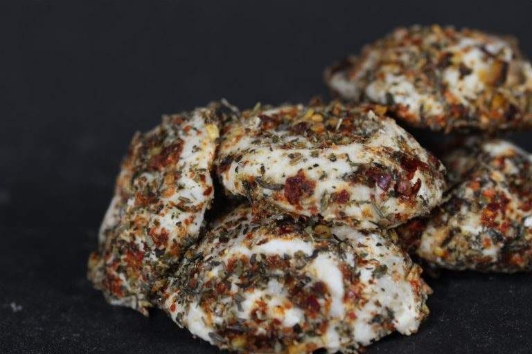 Chili-coated ġbejna cheeses on a dark background