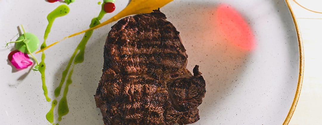 A plated grilled steak served at a waterfront restaurant