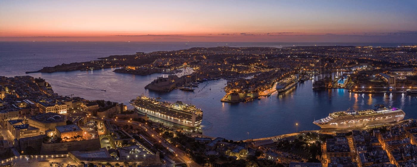 Aerial view of Valletta and the Grand Harbour at dusk with a cruise ship alongside