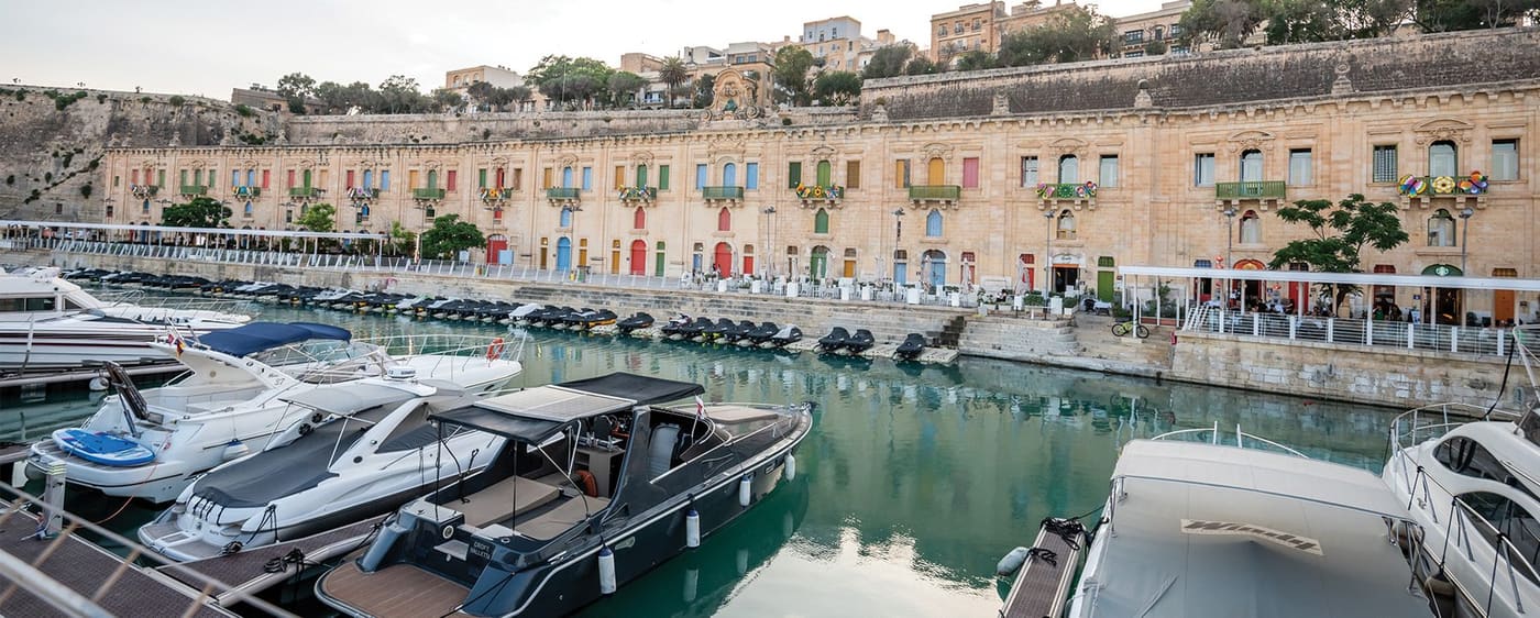 Colourful doors along the Valletta Waterfront quay with yachts in the foreground