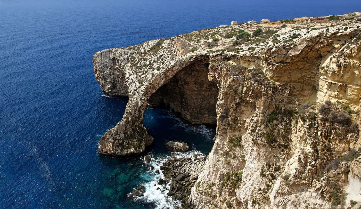 The natural rock arch of the Blue Grotto above deep blue sea
