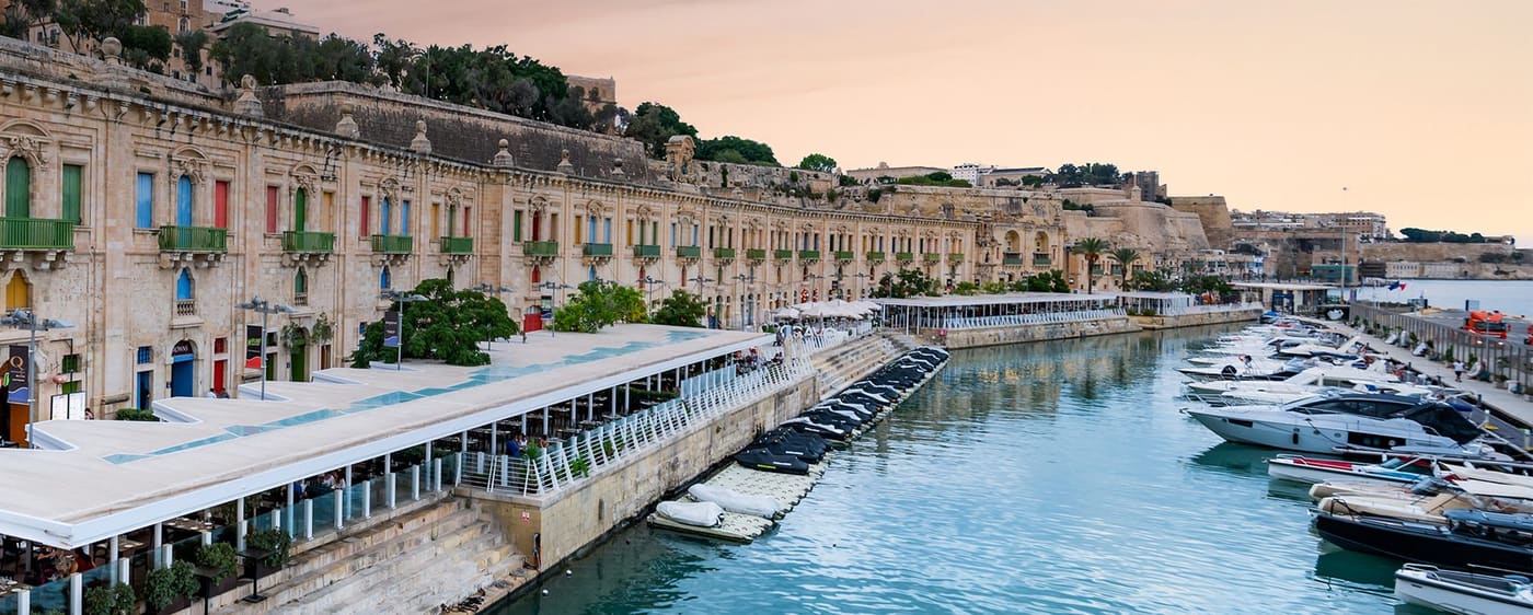 Waterfront buildings and harbour at sunset with restaurant terraces