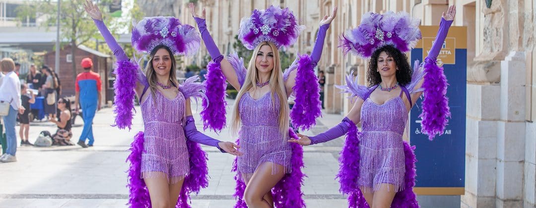 Three dancers in purple feathered costumes at Colour Fest