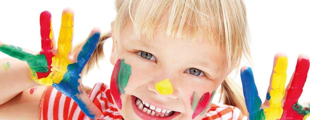 A smiling child with painted face and hands at a family event