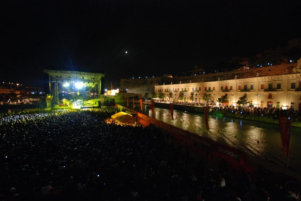Open-air stage and crowd on the waterfront at night