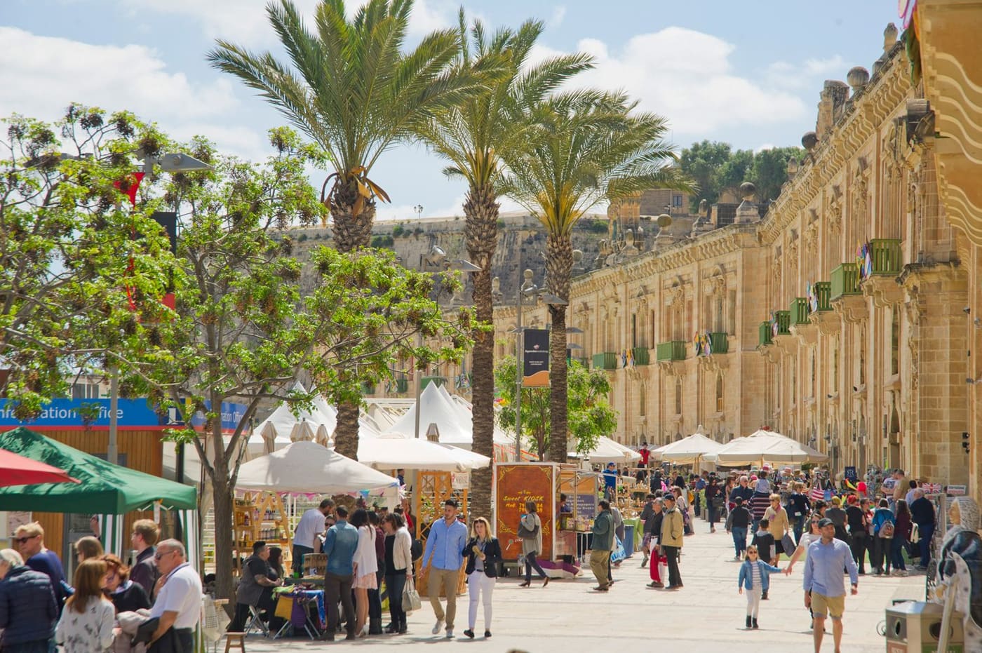 The Valletta Waterfront promenade with palm trees, market stalls and visitors