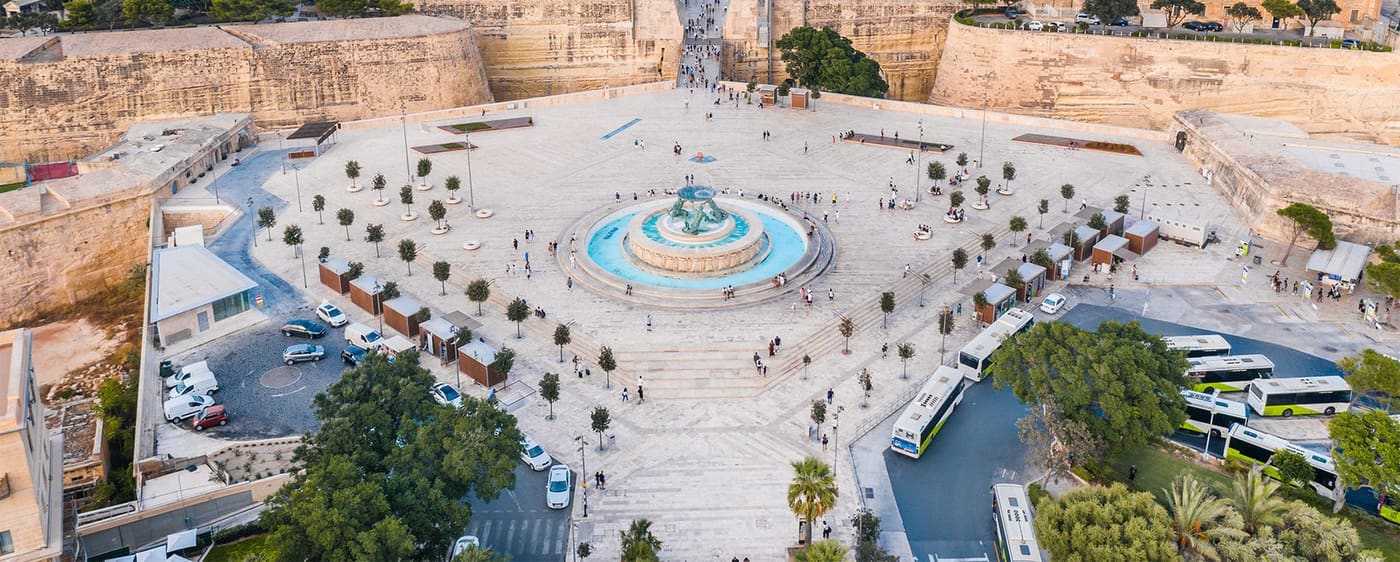 Aerial view of the fountain square outside Valletta's gate with a bus and walkers