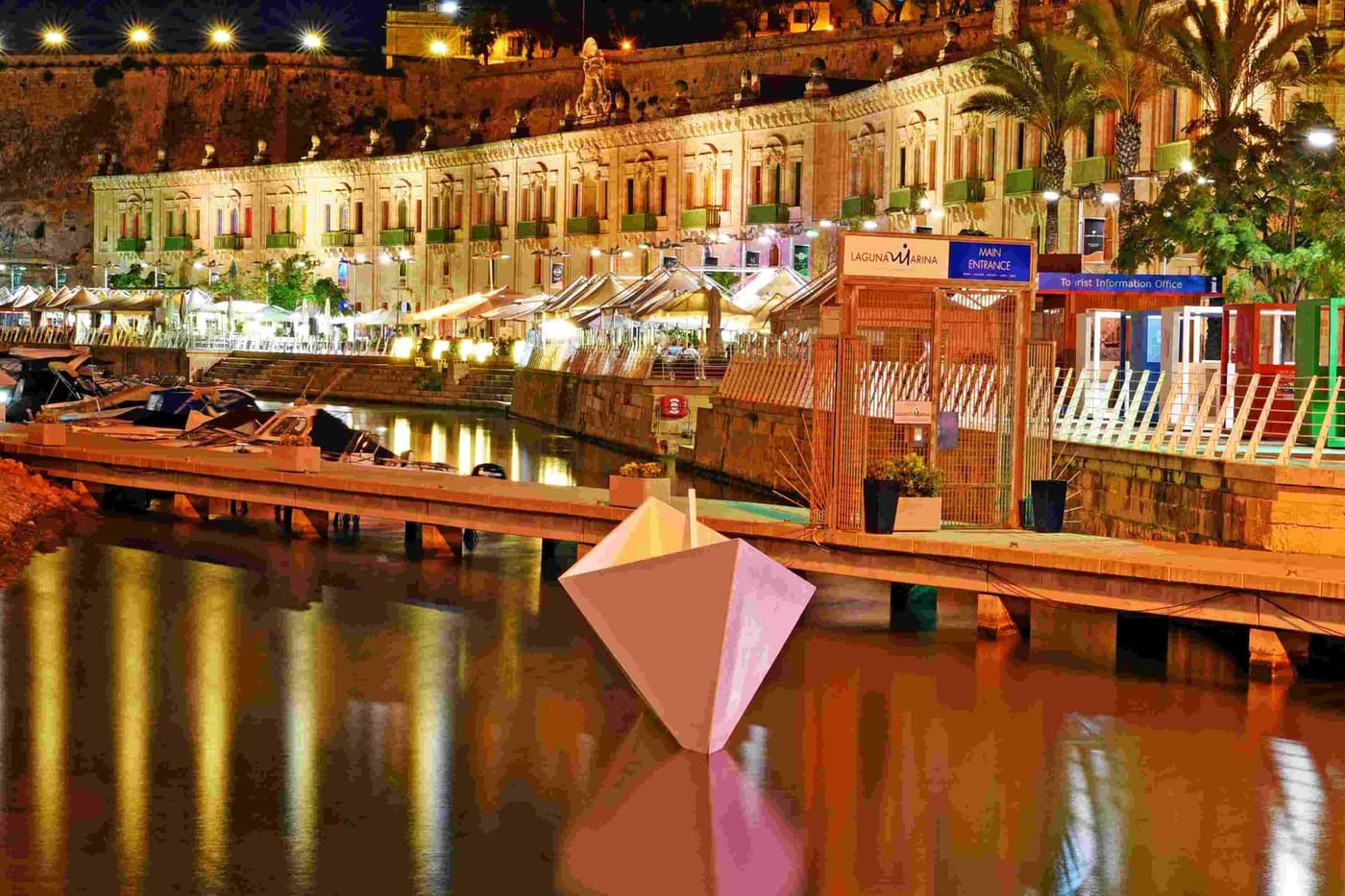 The lit waterfront frontage reflected in the harbour at night