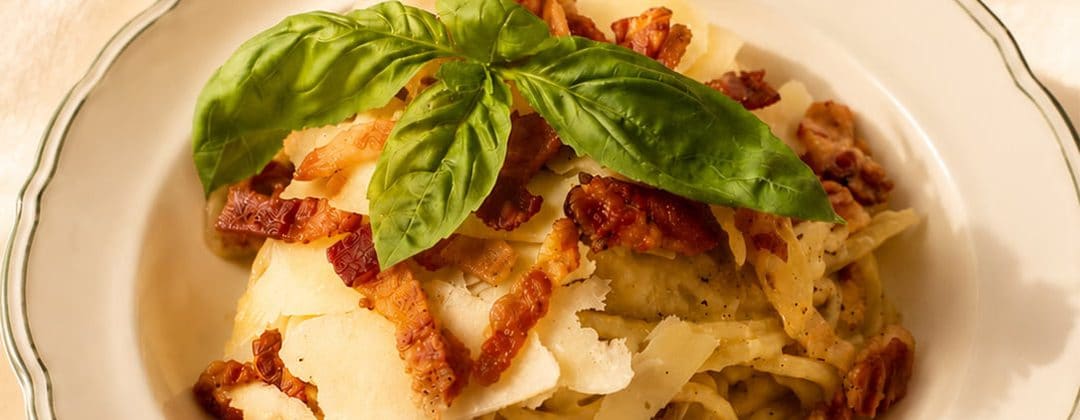 Pasta topped with crisp bacon, parmesan and fresh basil