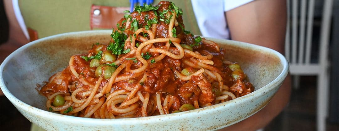 A bowl of spaghetti with tomato sauce and parsley