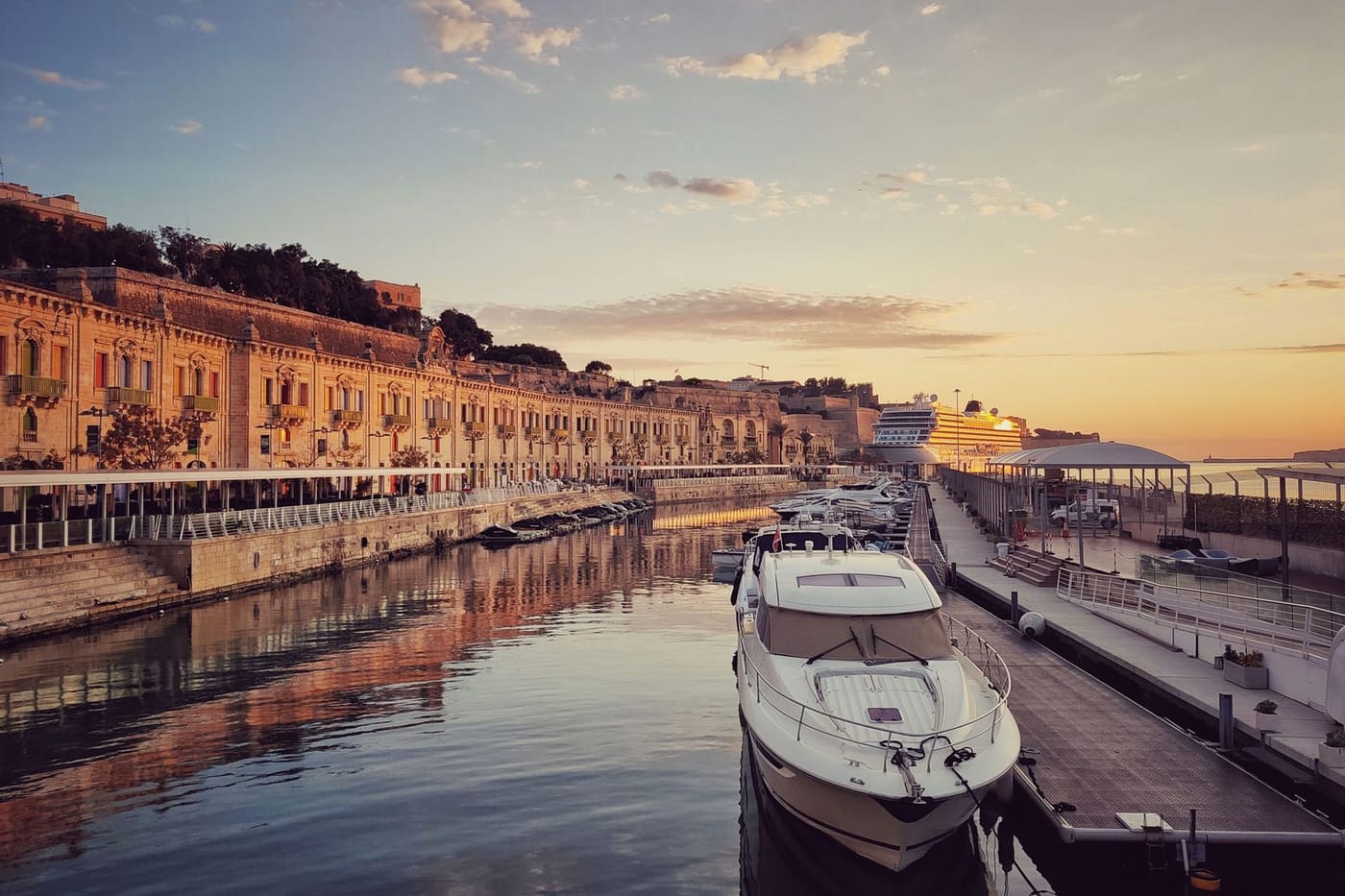 The historic harbourside quay at golden hour with moored boats and a cruise ship