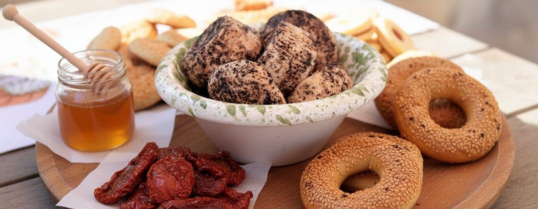 A bowl of Maltese delicatessen foods with sun-dried tomatoes, honey and bread rings