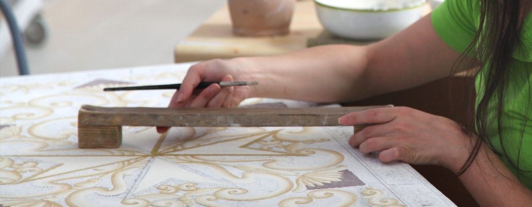 A craftsperson painting a delicate pattern on ceramics